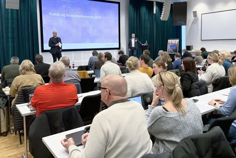 To personer på en scene foran et stort publikum i en konferansesal
