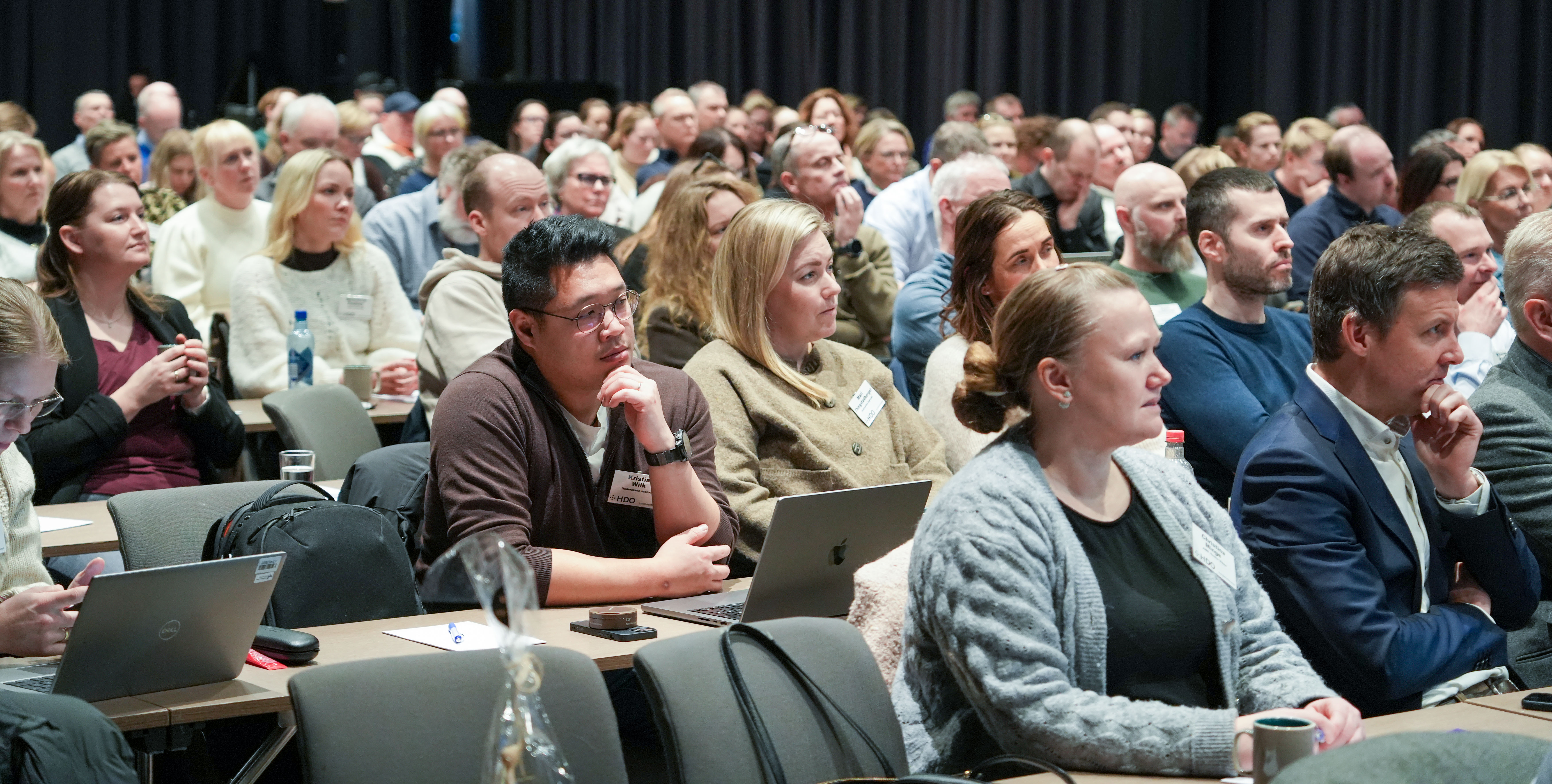 En gruppe mennesker som sitter i en konferansesal.