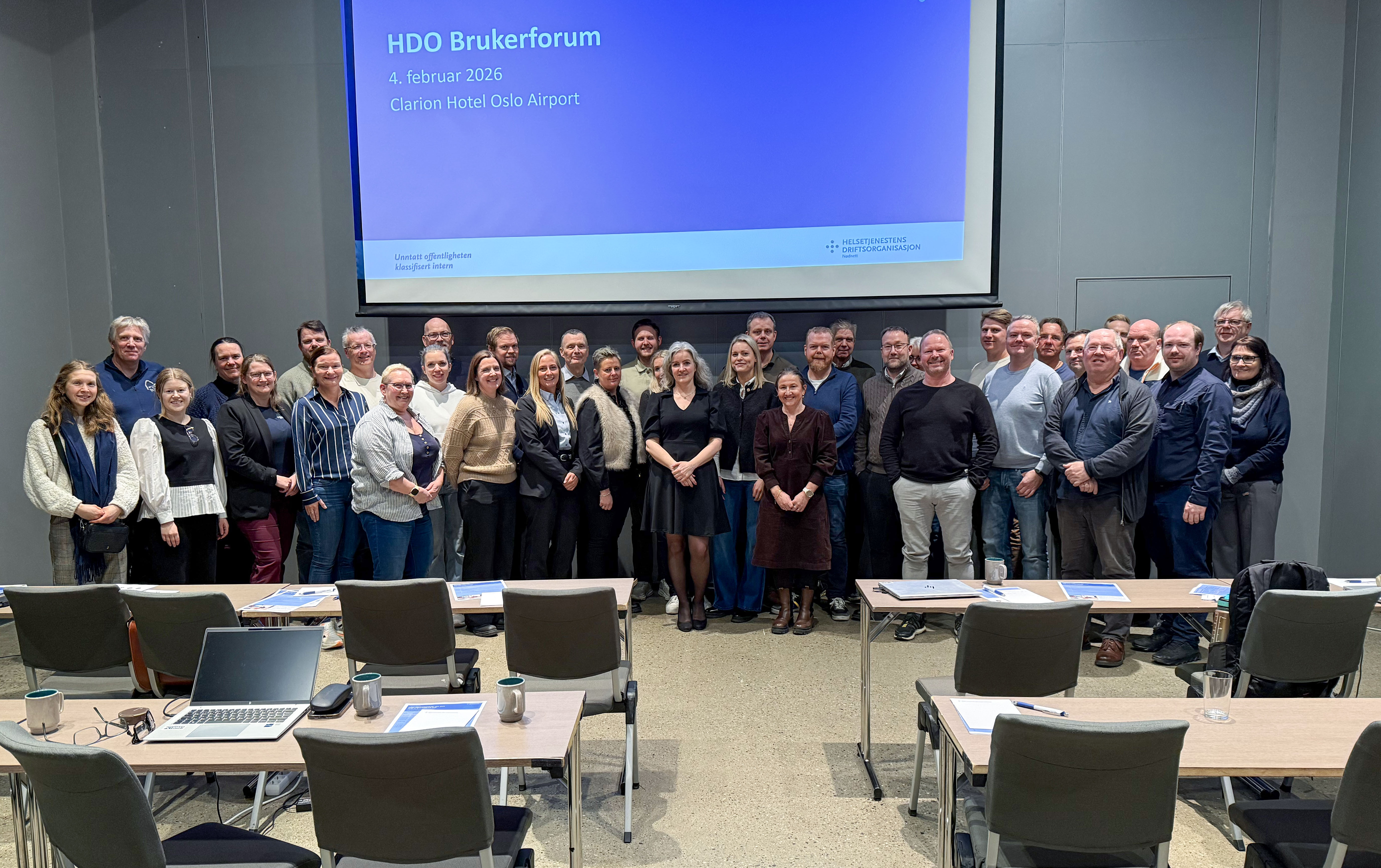 En gruppe mennesker som poserer for et bilde foran en projektorskjerm