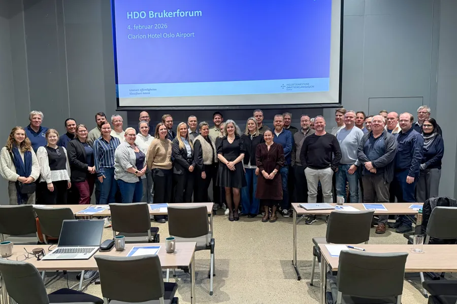 En gruppe mennesker som poserer for et bilde foran en projektorskjerm