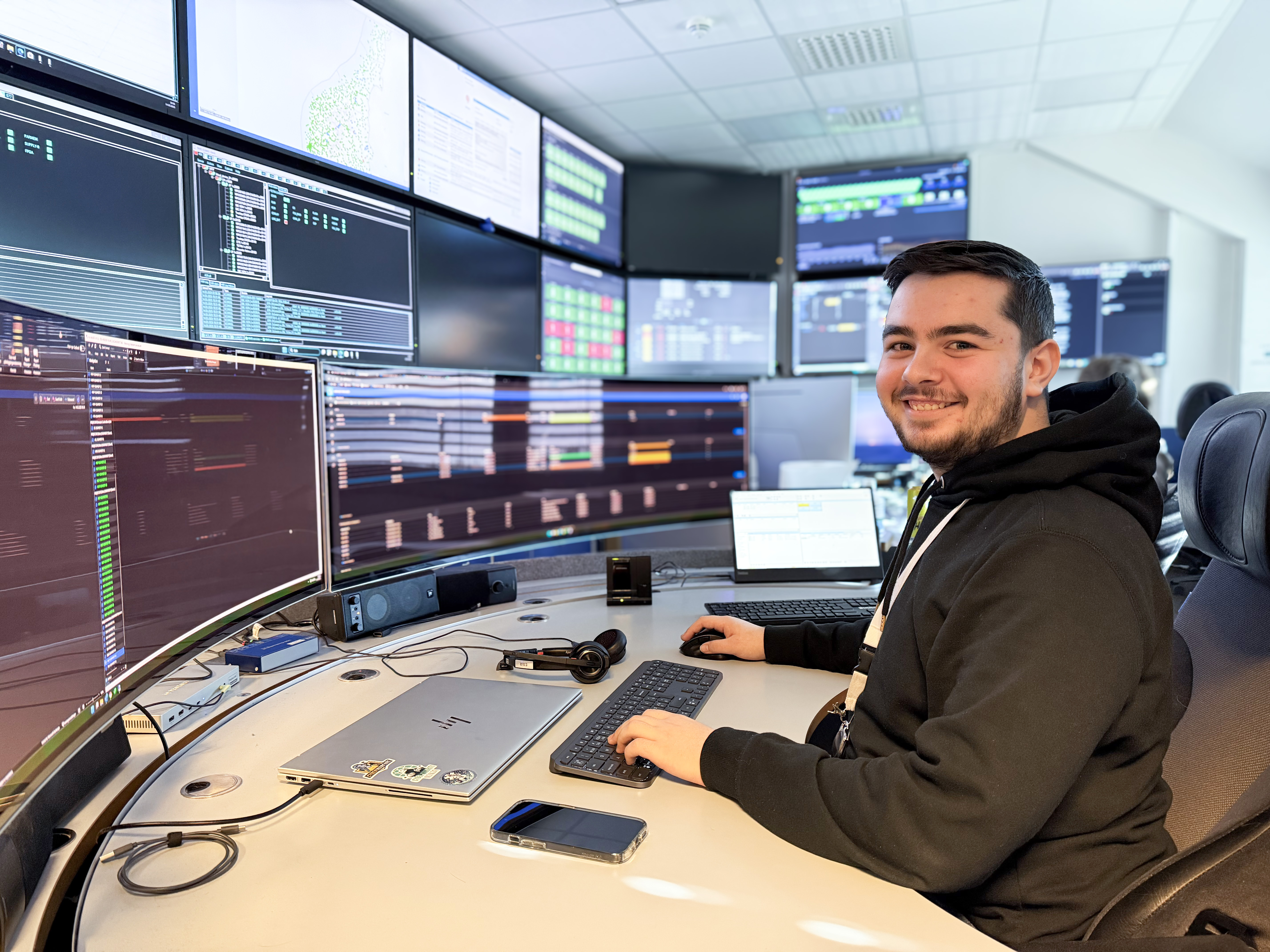 En mann som sitter ved et skrivebord med mange skjermer