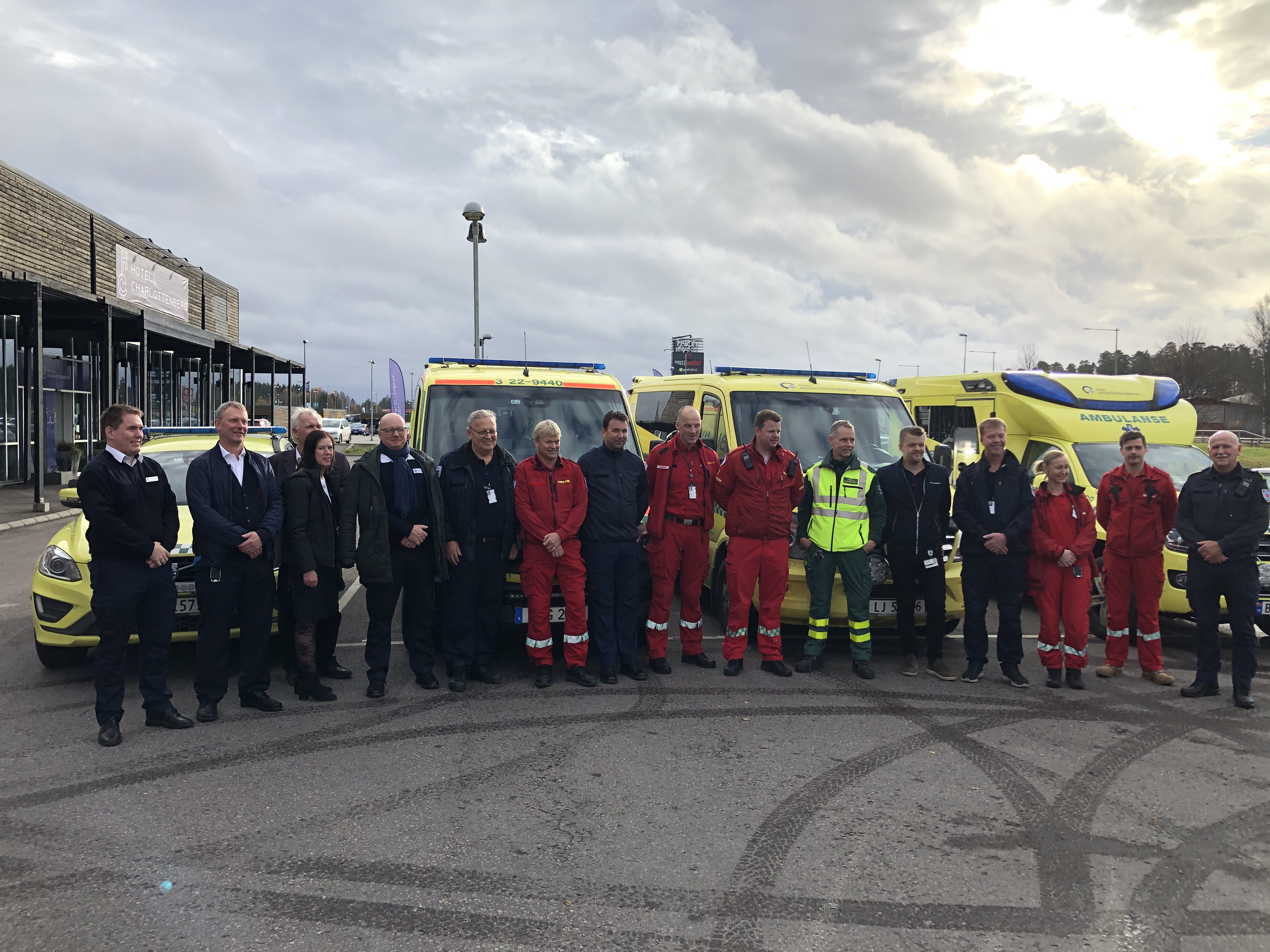 Bilde av mange mennesker, hvorav mange ambulansearbeidere foran ambulanser, alle på rad