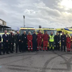 Bilde av mange mennesker, hvorav mange ambulansearbeidere foran ambulanser, alle på rad