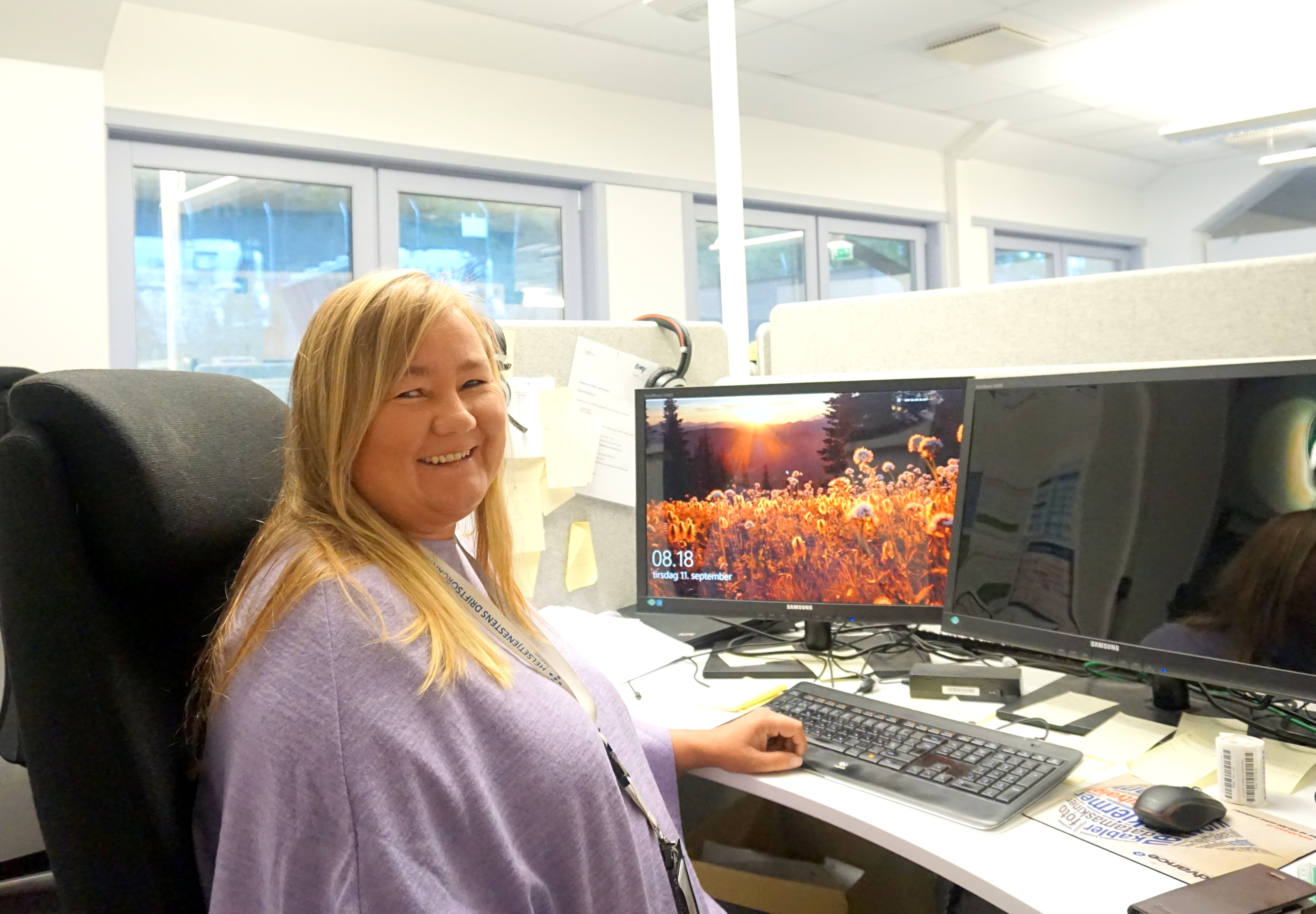 En kvinne som sitter ved et skrivebord med en datamaskin og et tastatur