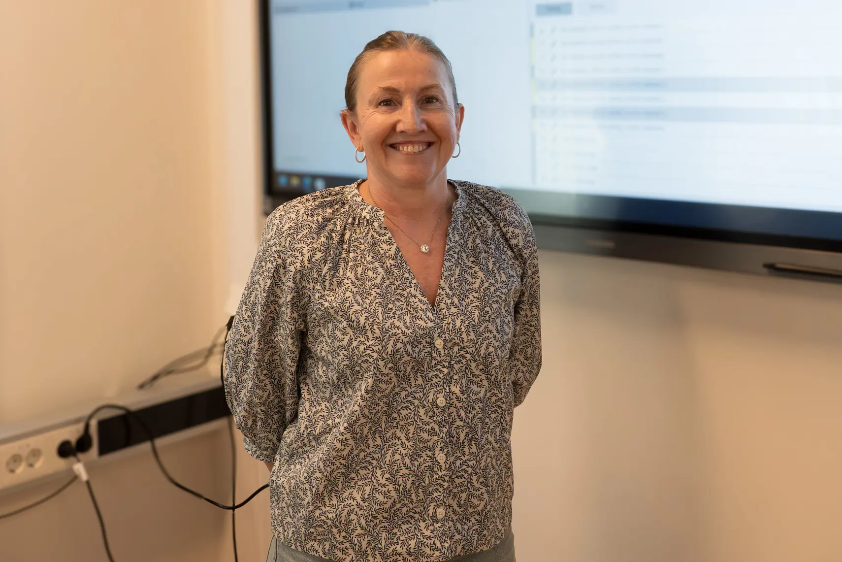 En dame som står foran en skjerm.