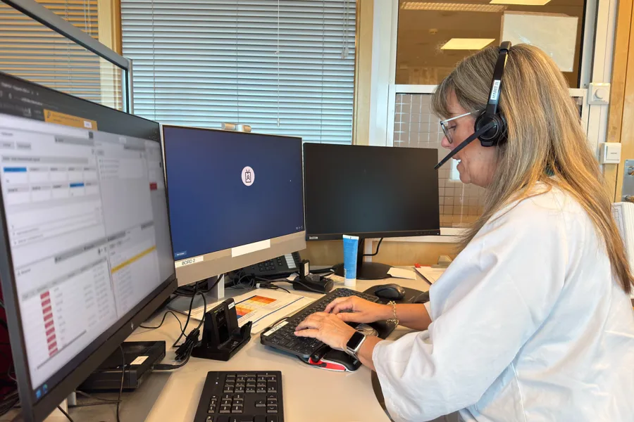 En person som har på seg hodetelefoner og sitter ved et skrivebord med en datamaskin