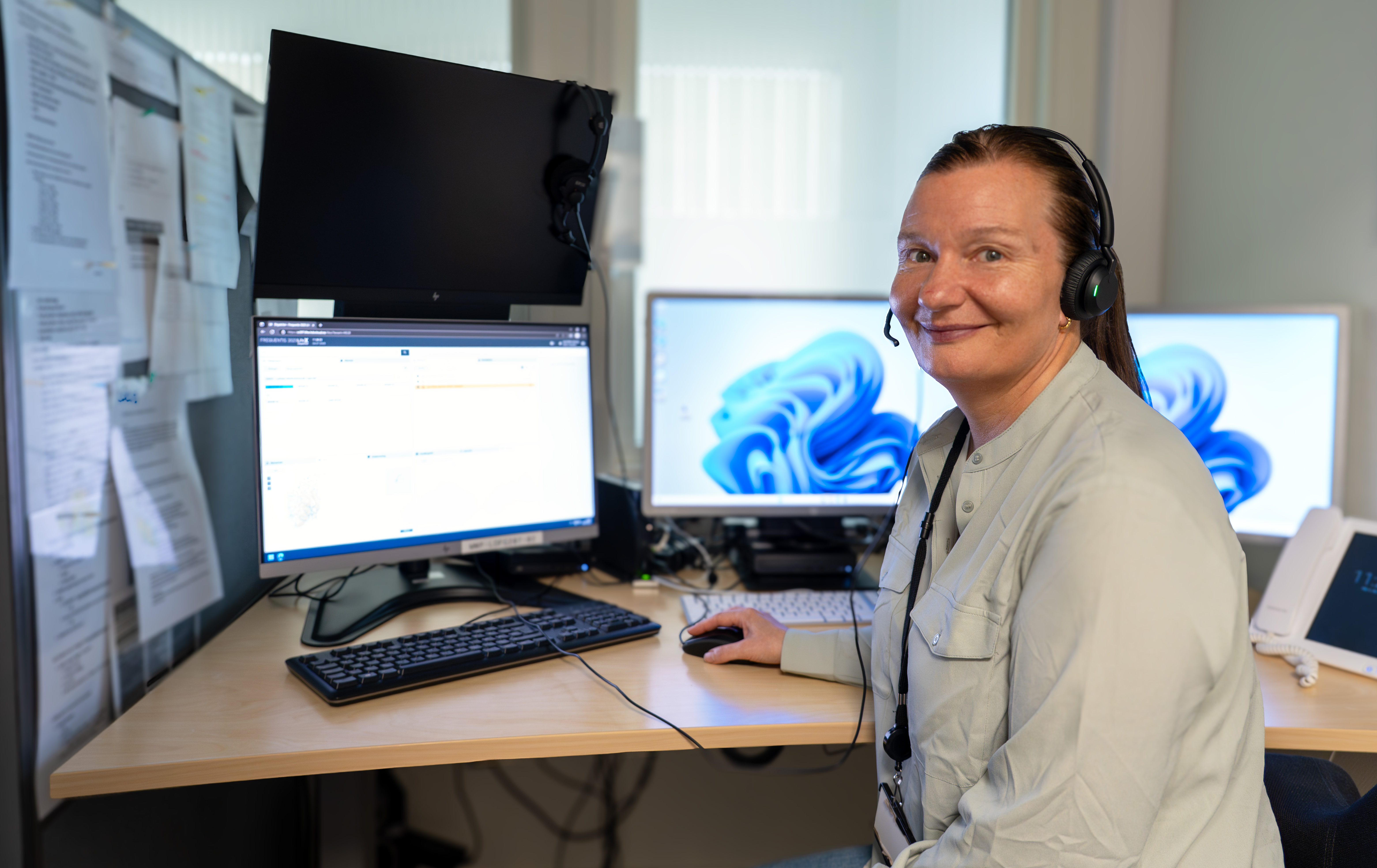 En person som har på seg hodetelefoner og sitter ved et skrivebord med en datamaskin