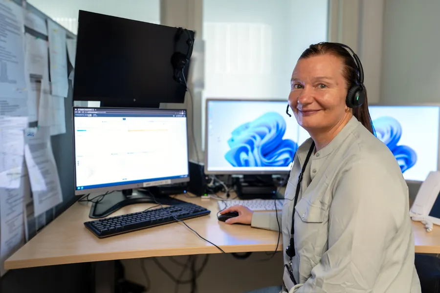 En person som har på seg hodetelefoner og sitter ved et skrivebord med en datamaskin