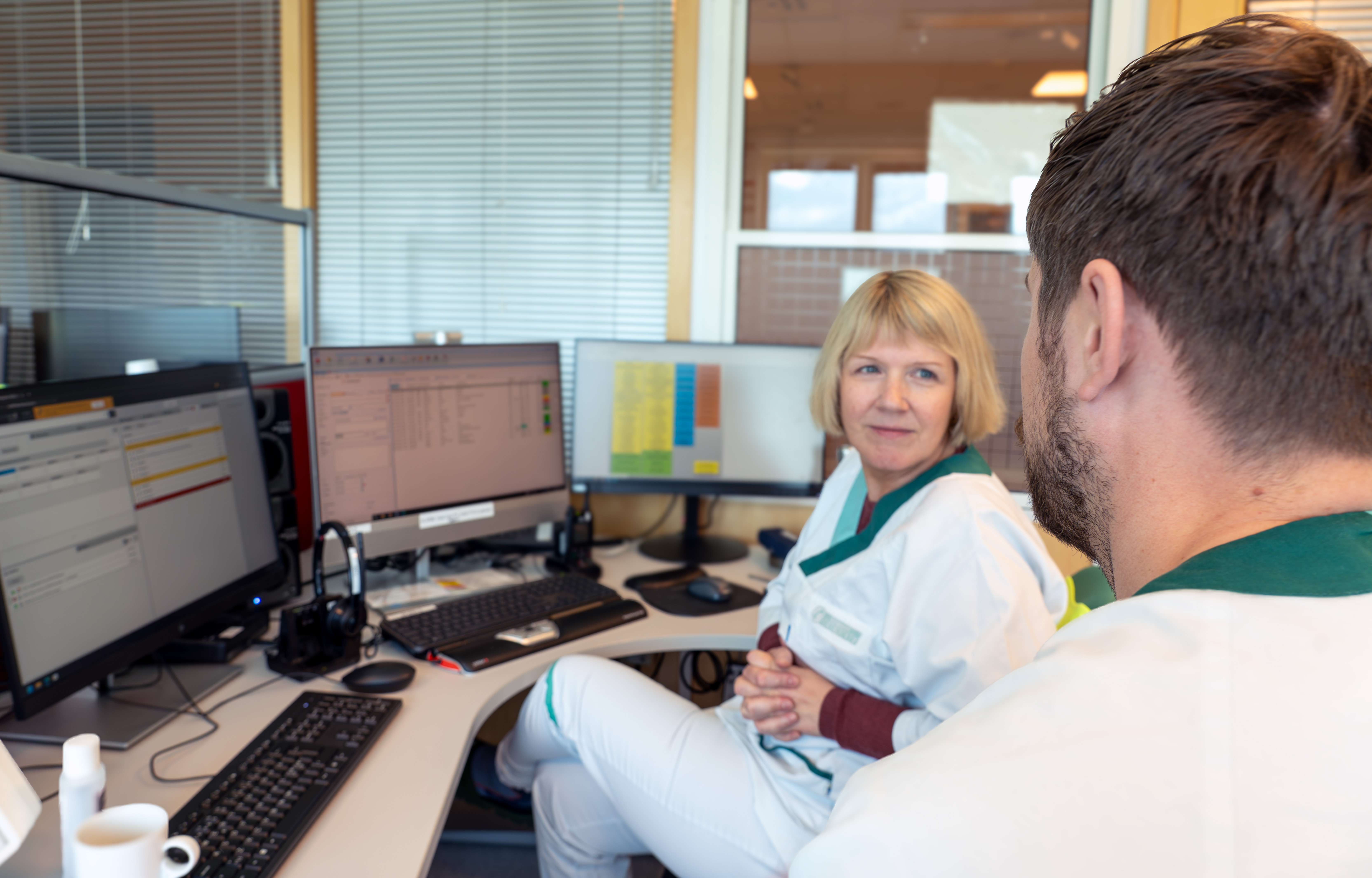 En mann og en kvinne som sitter ved et skrivebord med datamaskiner