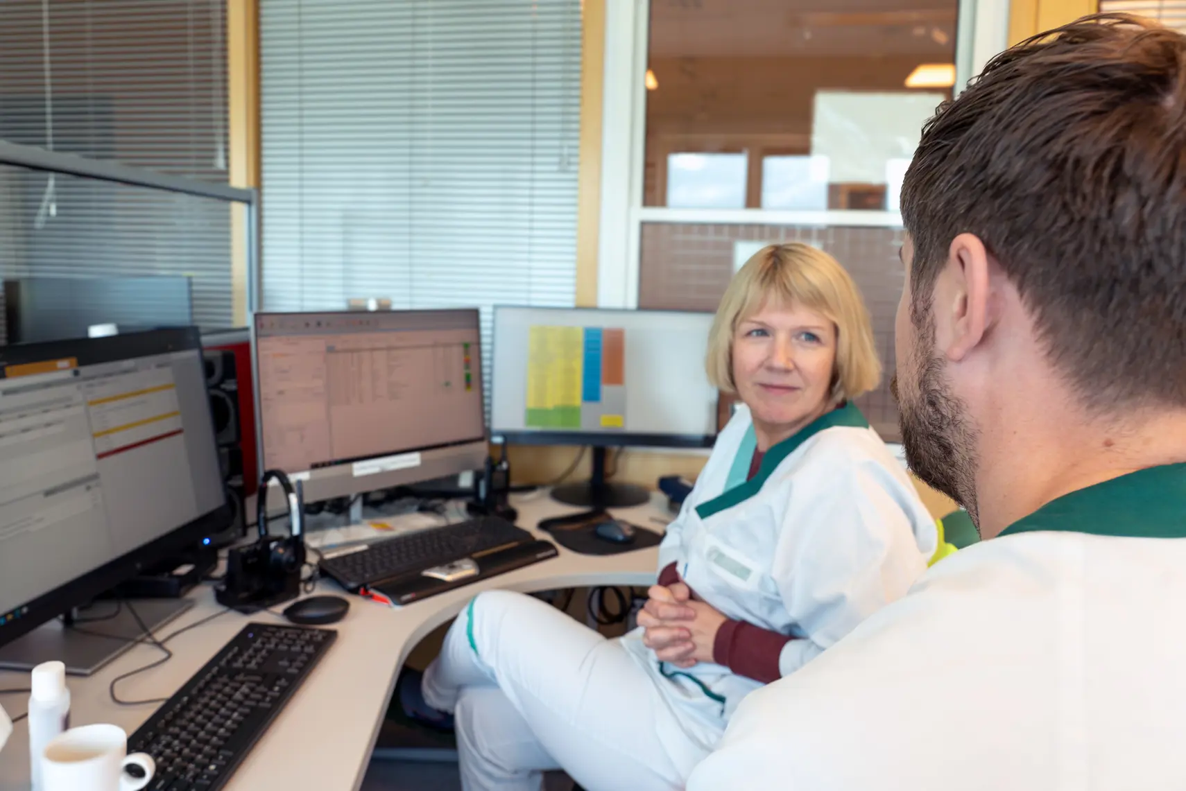 En mann og en kvinne som sitter ved et skrivebord med datamaskiner